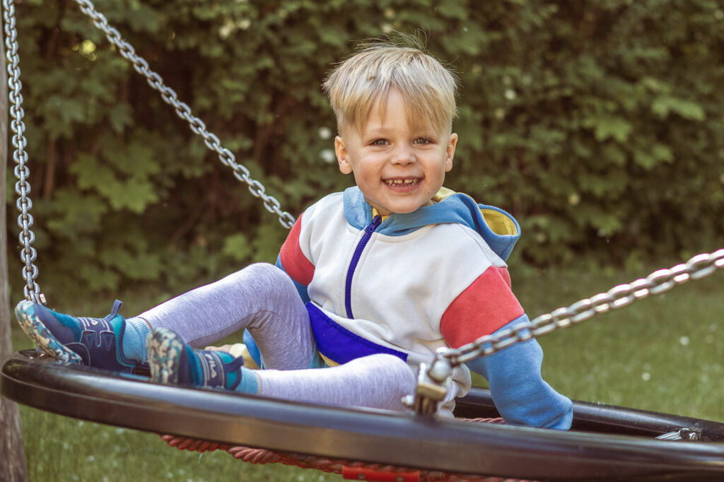 Junge auf Nestschaukel, Kindergartenfotografie im freien Spiel Berlin