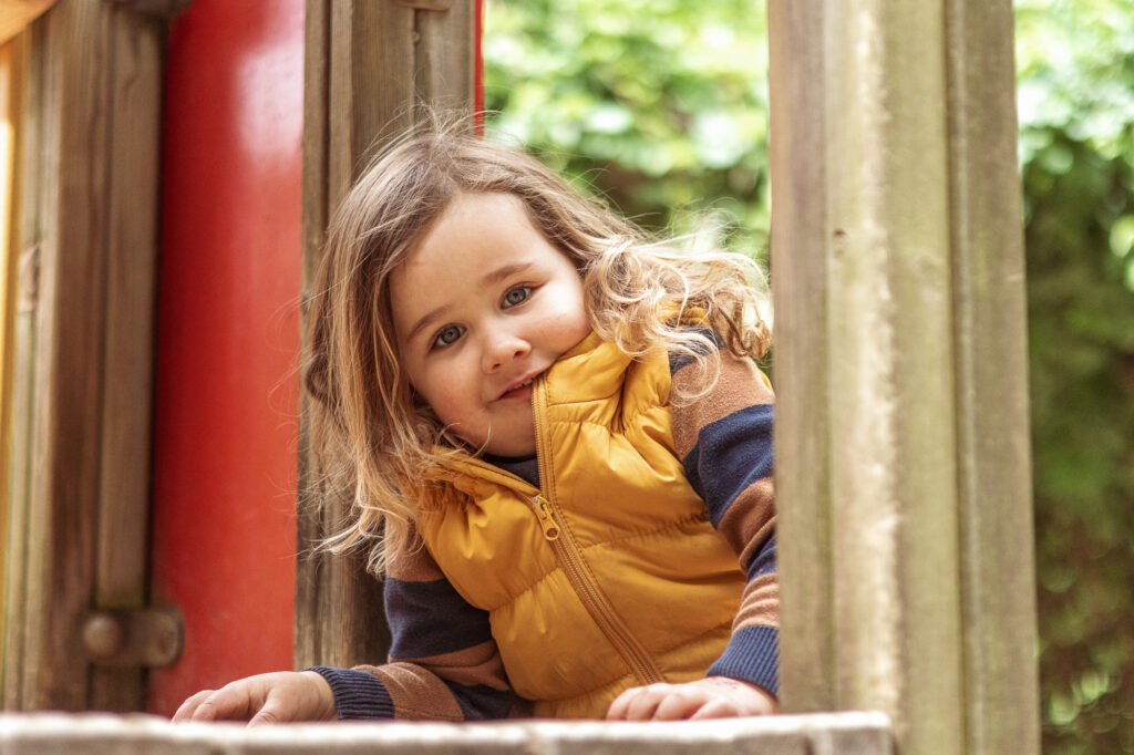 Mädchen auf Klettergerüst, Kindergartenfotografie im freien Spiel Berlin