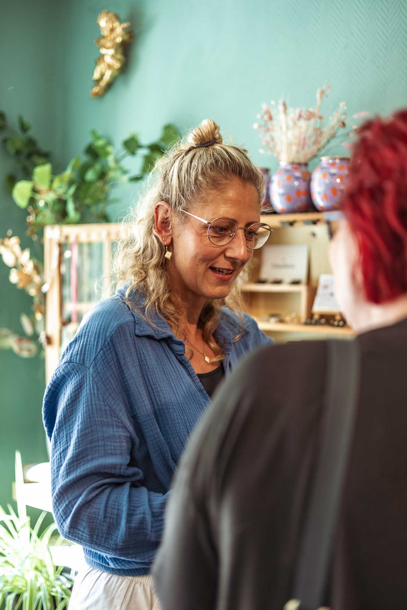 Portraitfotografie im Schmuckladen Liebling Strausberg: Ladenbesitzerin berät Kundin zu handgefertigtem Schmuck aus Blüten, authentische Businessfotografie für kreative Marken.