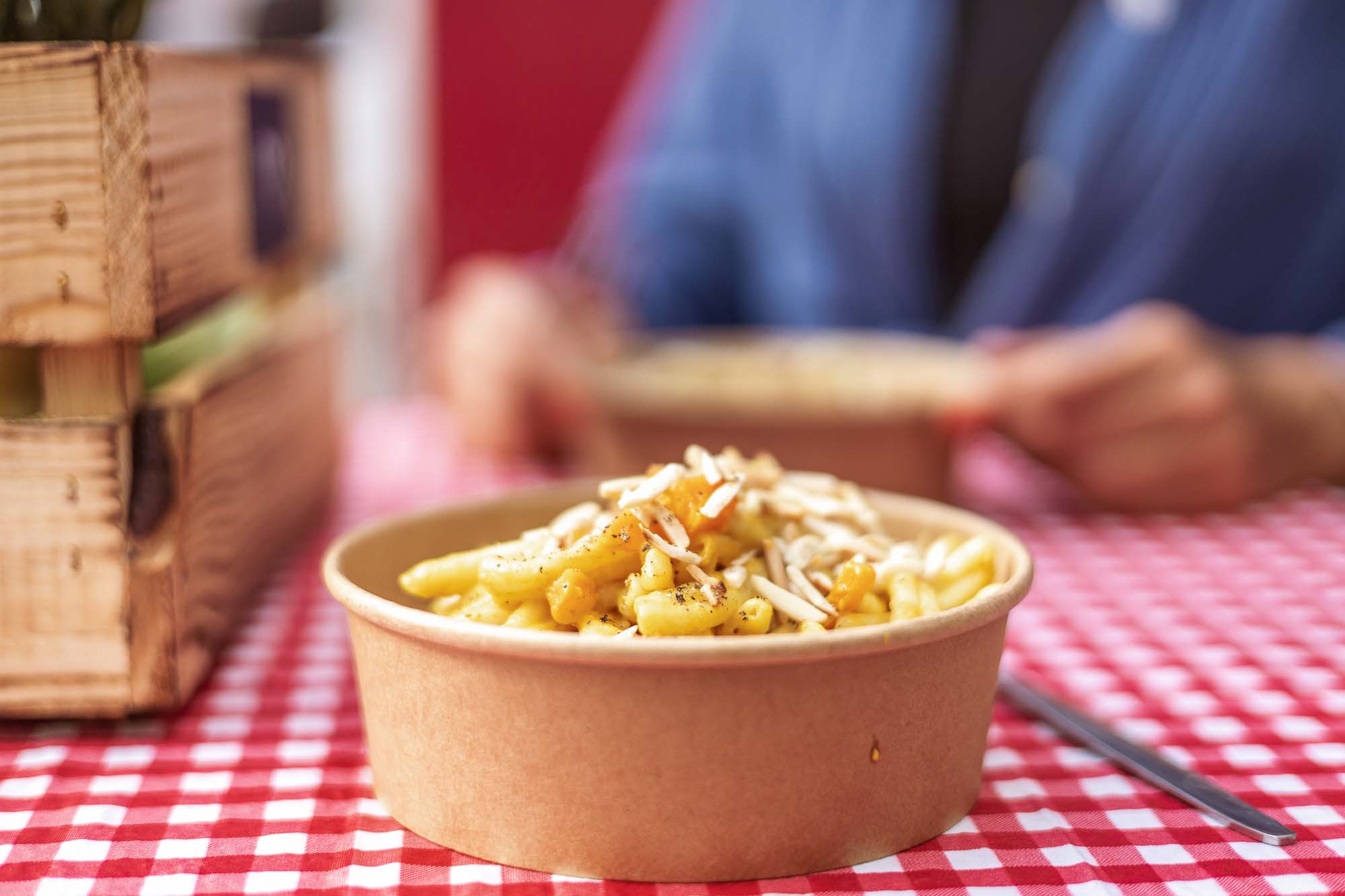 Authentische Businessfotografie Berlin: Schale mit frischer Pasta, vegetarisches Nudelgericht mit Käse und Nüssen, serviert auf rot-weiß karierter Tischdecke, Branding für Foodtruck und Gastronomie.