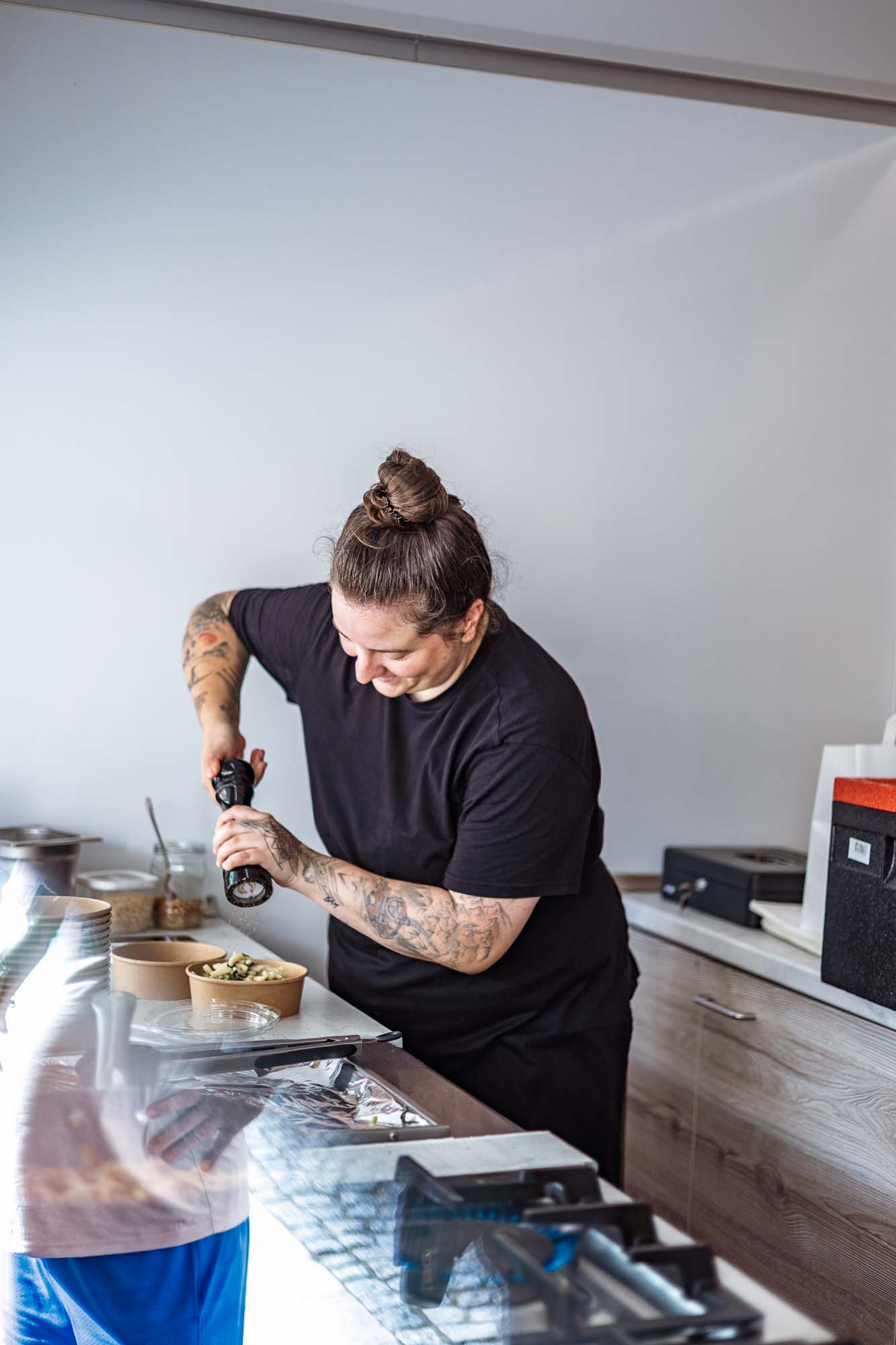 Authentische Unternehmensfotografie Berlin: Köchin würzt Pasta mit frischem Pfeffer im Foodtruck Pasta Perle, Businessfotografie Gastronomie mit Fokus auf Handwerk und Qualität.